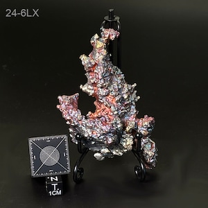 May include: A large, iridescent, metallic, purple, and red mineral specimen on a black stand. The mineral is shaped like a flame and has a rough, textured surface. The specimen is approximately 6 cm tall.