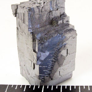 Pu&ograve; includere: Un grande esemplare minerale metallico grigio con una struttura cristallina cubica. Il minerale &egrave; alto circa 2,5 cm e ha una superficie ruvida e testurizzata.