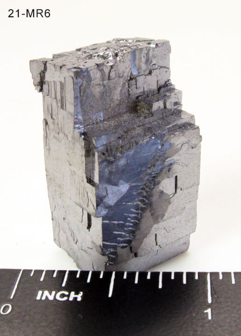 Pu&ograve; includere: Un grande esemplare minerale metallico grigio con una struttura cristallina cubica. Il minerale &egrave; alto circa 2,5 cm e ha una superficie ruvida e testurizzata.