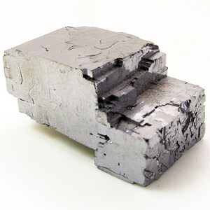 Pu&ograve; includere: Un grande cristallo cubico metallico grigio con una superficie ruvida e testurizzata.