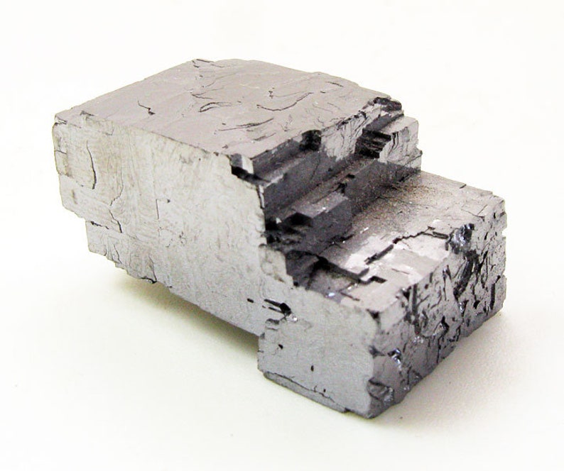 Pu&ograve; includere: Un grande cristallo cubico metallico grigio con una superficie ruvida e testurizzata.
