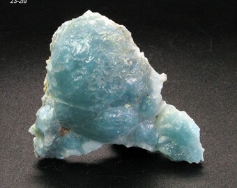 May include: A blue-green, irregularly shaped mineral specimen with a rough, textured surface. The mineral has a translucent appearance and is likely a type of chalcedony.