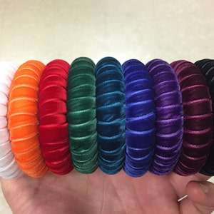 以下が含まれることがあります： 白、オレンジ、赤、緑、ティール、青、紫、黒のレインボーカラーのベルベット製ヘアバンド8個セット。 各ヘアバンドは単色で、リブ編みのテクスチャです。