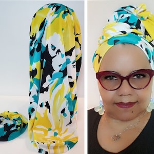 May include: A yellow, turquoise, and black floral print satin scarf. The scarf is shown tied around a person's head in a turban style.