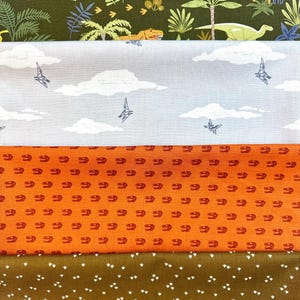 May include: Four different fabric swatches with dinosaur and other animal prints. The top swatch is a dark green fabric with a white dinosaur print. The second swatch is a light gray fabric with a white cloud and bird print. The third swatch is an orange fabric with a red dinosaur print. The bottom swatch is a brown fabric with a white footprint print.