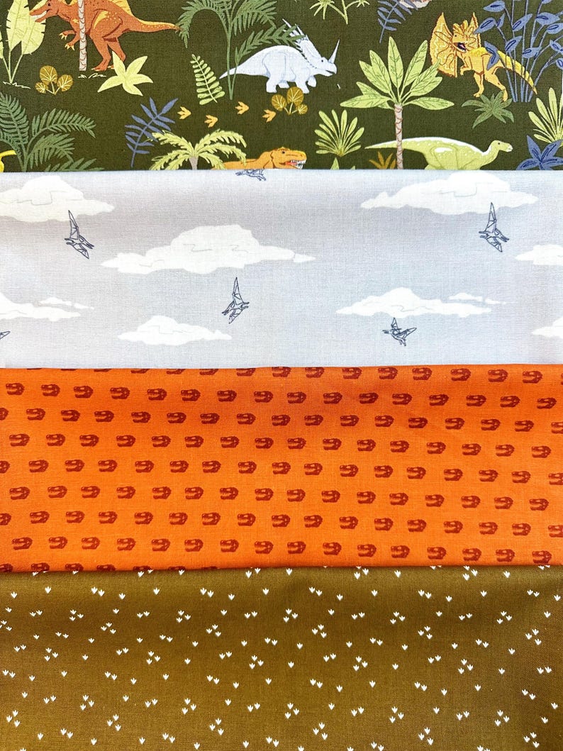 May include: Four different fabric swatches with dinosaur and other animal prints. The top swatch is a dark green fabric with a white dinosaur print. The second swatch is a light gray fabric with a white cloud and bird print. The third swatch is an orange fabric with a red dinosaur print. The bottom swatch is a brown fabric with a white footprint print.