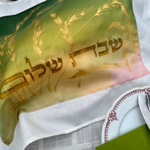 Shabat Shalom, Trigo Dourado em Verde e Amarelo Capa de Pão de seda pintada à mão. Texto com letras grandes, em amarelo, sobre fundo de cor creme.