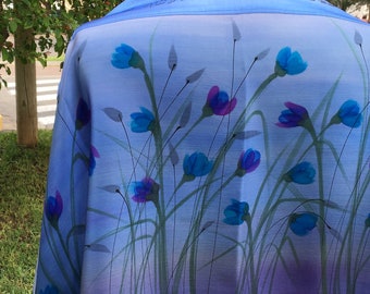 May include: A blue and purple silk tallit with a Hebrew inscription and a floral design featuring blue flowers and green stems.