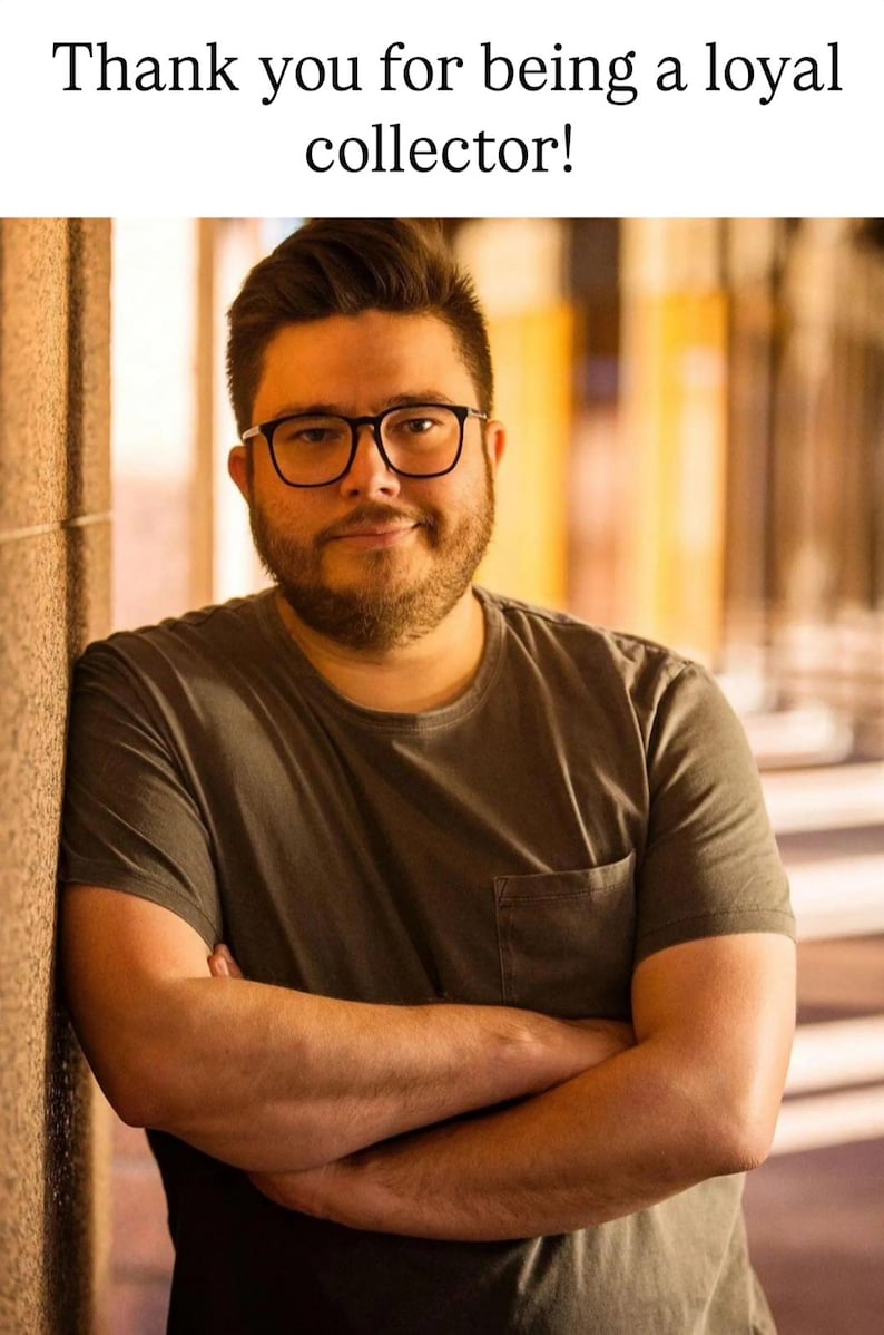 K&ouml;nnte beinhalten: Eine Person mit Brille und einem grauen T-Shirt mit Tasche lehnt an einer Wand. Der Text oben lautet: "Vielen Dank, dass Sie ein treuer Sammler sind!"