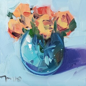 Puede incluir: Pintura al óleo de un ramo de flores naranjas y amarillas en un jarrón de cristal azul claro. El jarrón está sobre un fondo azul claro con una sombra púrpura. La obra está firmada en la esquina inferior izquierda.