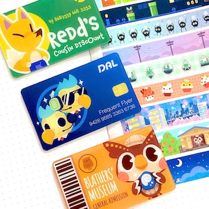 Puede incluir: Un conjunto de tarjetas coloridas y cinta decorativa con personajes de dibujos animados y diseños. Las tarjetas incluyen "Redd's Cousin Discount", "DAL Frequent Flyer" y "Blathers' Museum General Admission". La cinta tiene varios patrones ilustrados.