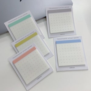 May include: A collection of transparent sticky notes with colored header strips in mint green, yellow, pink, and blue. Each note has a grid of small dots and the text "TRANSPARENT STICKY NOTES" and "oddloop". The notes are on white backing cards.
