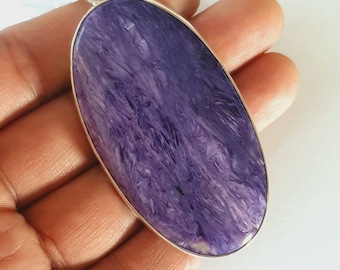 May include: A silver pendant featuring a large, oval-shaped purple stone with a swirling pattern.