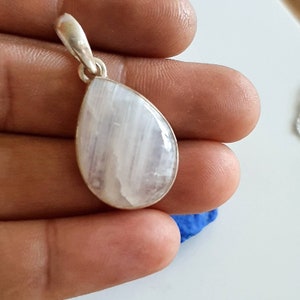 May include: A teardrop-shaped pendant with a white gemstone set in silver.