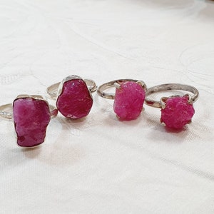 May include: Four silver rings with pink ruby gemstones. The rings are set with rough, uncut stones.