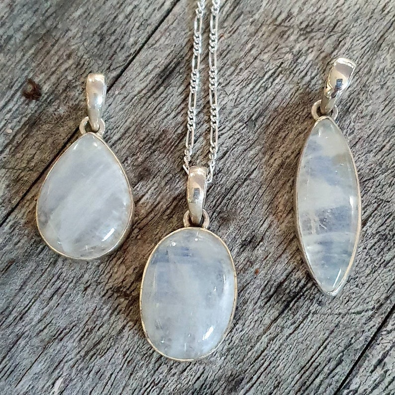May include: Three silver necklaces with moonstone pendants. The pendants are different shapes: teardrop, oval, and oval with a pointed end.