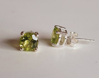 Puede incluir: Un par de pendientes de botón de plata con piedras preciosas de peridoto verde.