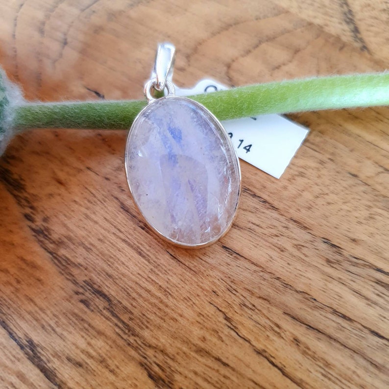 May include: A silver pendant with a large oval-shaped moonstone. The moonstone is translucent and has a light blue iridescent sheen.