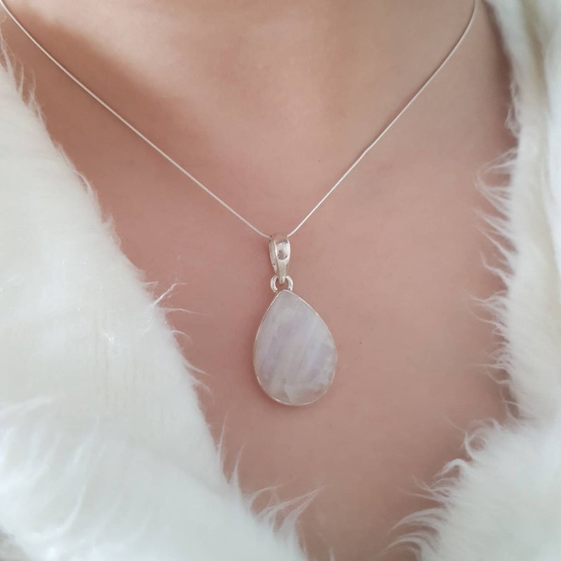 May include: A silver chain necklace with a teardrop-shaped moonstone pendant.
