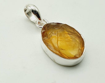 May include: A silver pendant with a large, oval-shaped, amber-colored gemstone. The pendant has a simple, elegant design.
