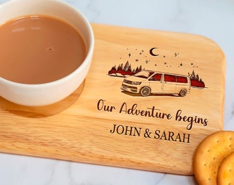 May include: A wooden serving tray with a white mug, a plate of biscuits, and an engraved design of a camper van, a crescent moon, and stars. The text "Our Adventure Begins" and "JOHN & SARAH" is engraved on the tray.