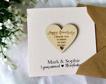 Könnte beinhalten: Eine weiße Karte mit einem daran befestigten Holzhertz. Das Herz trägt den Text "Happy Anniversary" und "5 Amazing Years, 60 Months, 260 Weeks, 1826 Days". Die Karte trägt auch den Text "Mark & Sophie, 5 years married, 9th September".