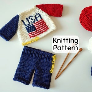 May include: Knitting pattern for a red, white, and blue knitted outfit for a doll or small toy. The outfit includes a sweater with the word "USA" and an American flag design, and blue pants.