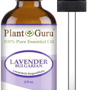 Op de afbeelding: Een bruine glazen fles Plant Guru Lavendel Bulgaarse etherische olie met een zwarte druppelaar. Het etiket bevat de tekst "100% Pure Essential Oil" en "2 fl oz.". De fles heeft een zwarte dop en een paars etiket.