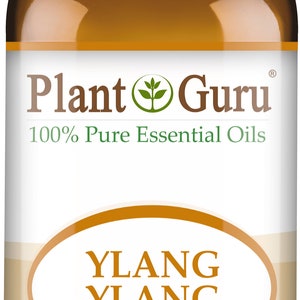May include: A brown glass bottle of Ylang Ylang essential oil with a white cap. The label reads "Plant Guru 100% Pure Essential Oils" and "Ylang Ylang Cananga Odorata 1 fl oz. (30 ml)." The bottle is labeled "Therapeutic Grade."