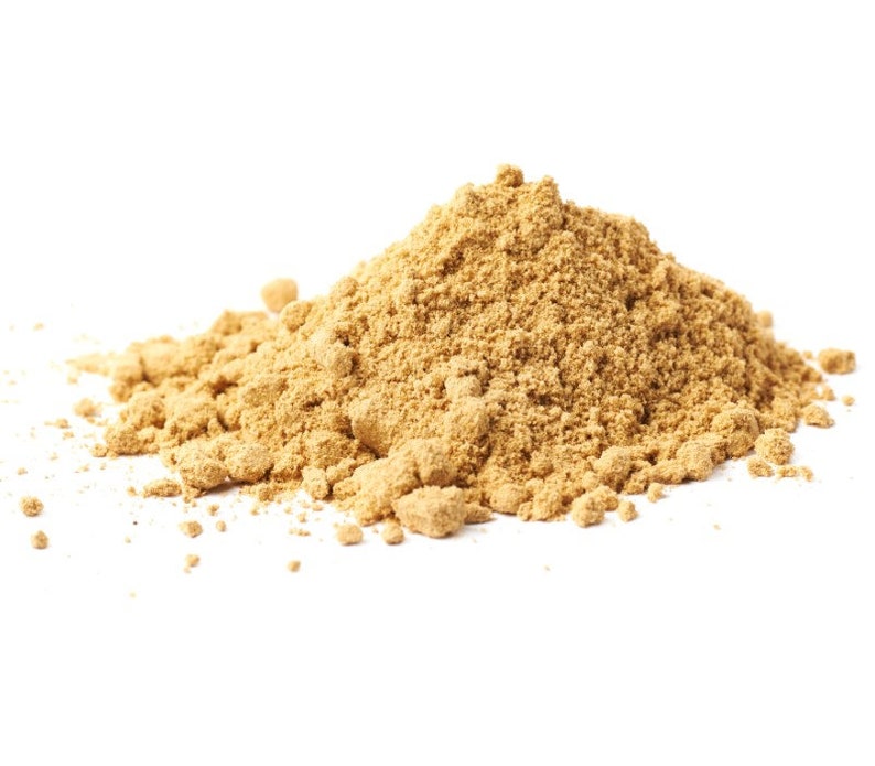 Puede incluir: Un mont&oacute;n de polvo marr&oacute;n claro, posiblemente una especia o ingrediente, sobre un fondo blanco. El polvo tiene una textura fina y granulada, pareciendo reci&eacute;n molido. La imagen est&aacute; bien iluminada, resaltando la textura y el color del polvo.