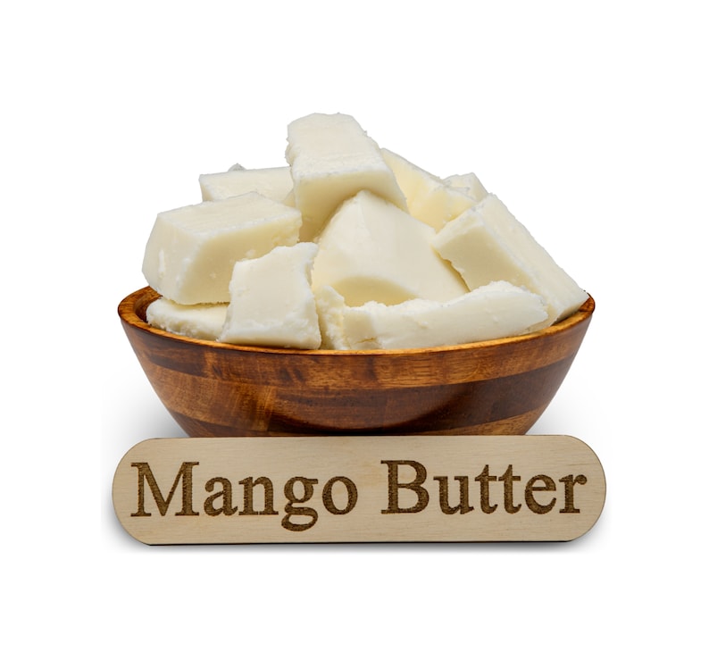 May include: A wooden bowl filled with chunks of white mango butter. The bowl is sitting on a white surface with a wooden sign that reads "Mango Butter".