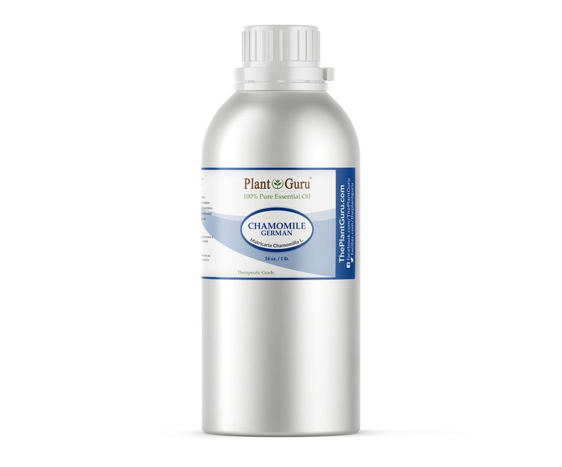 May include: A silver metal bottle with a white cap and a label that reads "Chamomile German" and "100% Pure Essential Oil." The label also includes the Plant Guru logo and states the contents are 16 fl oz / 1 lb. The bottle is cylindrical.