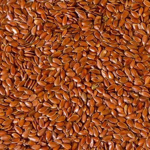 May include: A close-up image of a large quantity of brown flax seeds.