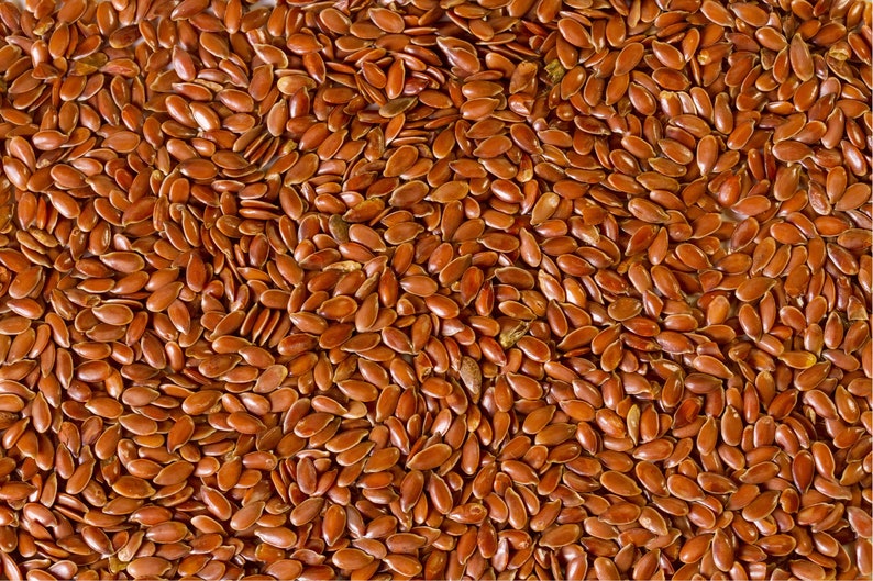 May include: A close-up image of a large quantity of brown flax seeds.