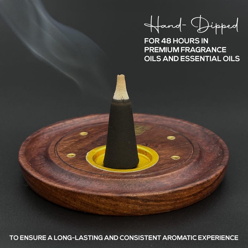 Op de afbeelding: Een zwarte wierookkegel in een houten houder met een goudkleurige basis. De houder is rond met een donkerbruine afwerking en kleine messing accenten. De tekst "Hand-Dipped" en andere tekst over het product zijn zichtbaar.