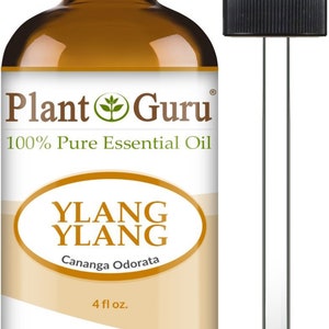 May include: A brown glass bottle of Ylang Ylang essential oil with a black dropper. The bottle has a white label with the text "Plant Guru" and "100% Pure Essential Oil". The label also reads "Ylang Ylang" and "Cananga Odorata". The bottle contains 4 fl oz.