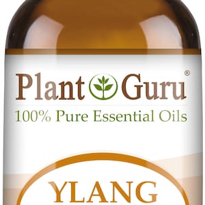 May include: A brown glass bottle of Plant Guru Ylang Ylang essential oil. The label features the text "YLANG YLANG" in a gold oval, with "Cananga Odorata" below. The bottle contains 1/3 fl oz (10 ml) of oil.