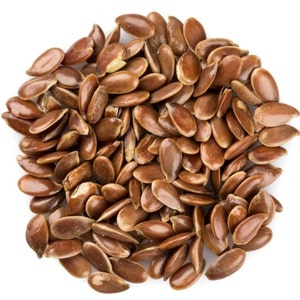 May include: A close-up view of a pile of brown flax seeds, also known as linseed, on a white background.