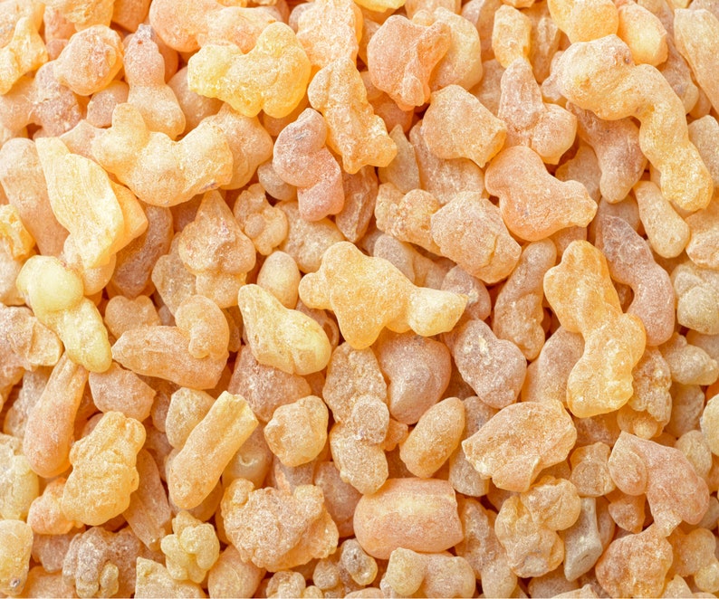 May include: A close-up image of a pile of pale yellow, irregularly shaped resin pieces. The resin is translucent and has a slightly rough texture.