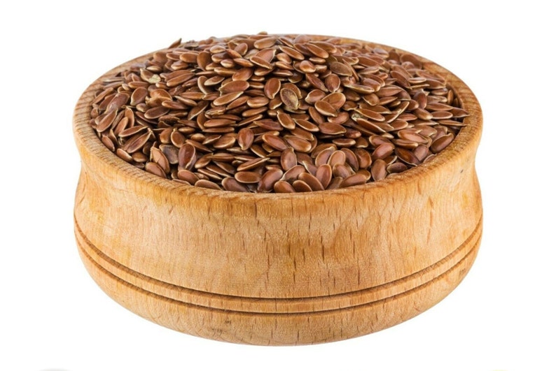 May include: A wooden bowl filled with brown flax seeds.