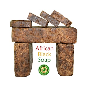 May include: A display of African Black Soap bars, arranged to resemble a structure. The soap is dark brown with a textured surface. The text "African Black Soap" is displayed in red, yellow, and green, with a "100% Natural Product" seal.
