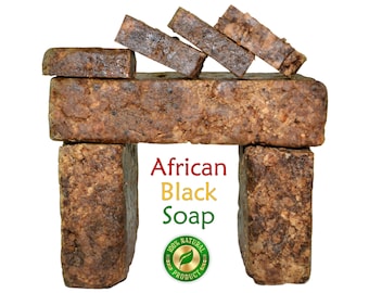 May include: A display of African Black Soap bars, arranged to resemble a structure. The soap is dark brown with a textured surface. The text "African Black Soap" is displayed in red, yellow, and green, with a "100% Natural Product" seal.