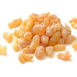 May include: A pile of pale yellow frankincense resin pieces, also known as olibanum, on a white background.