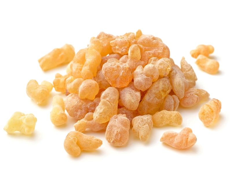 May include: A pile of pale yellow frankincense resin pieces, also known as olibanum, on a white background.