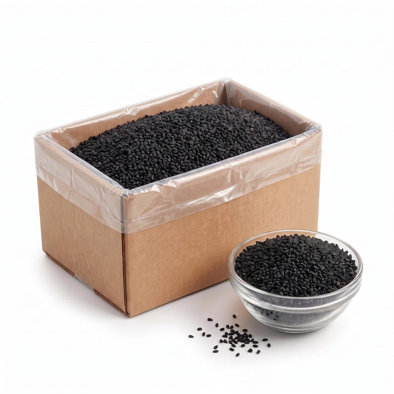 May include: A rectangular brown cardboard box lined with clear plastic and filled with small, dark black seeds. Next to the box is a clear glass bowl also filled with the same black seeds, with a few scattered on the surface nearby.