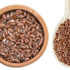 May include: A wooden bowl and spoon filled with brown flax seeds.