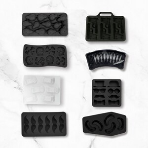 May include: Set of nine black and white silicone ice cube trays with various shapes, including skulls and crossbones, guns, bullets, moustaches, and a coffin.