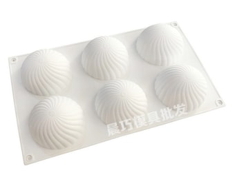 Könnte beinhalten: Weiße Silikonform mit sechs runden Vertiefungen, jede mit einem Wirbelmuster. Die Form ist zum Backen oder Herstellen von Desserts gedacht.