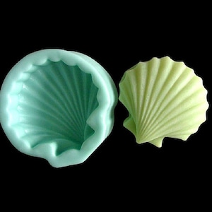 May include: A light green silicone mold shaped like a seashell. The mold is shown next to a light green seashell made from fondant.