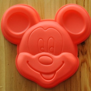 Può includere: Stampo in silicone rosso a forma di testa di Topolino. Lo stampo presenta dettagli precisi, tra cui le orecchie, gli occhi, il naso e la bocca di Topolino.